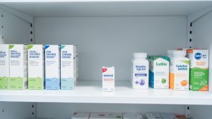 Étagère de pharmacie avec un emplacement vide et plusieurs produits de santé alternatifs non identifiés.