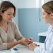 Une femme adulte mesure calmement son pouls au poignet lors d’une consultation médicale, sous le regard attentif d’une professionnelle de santé.