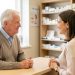Un homme senior de plus de 65 ans échange calmement avec une pharmacienne au sujet des vaccins contre la grippe et la Covid-19 dans une pharmacie lumineuse et rassurante.